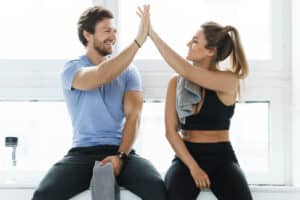 High five between man and woman in the gym after fitness workout. Personal trainer and his client achieving results during a training.