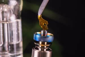 Macro detail of dabbing tool with small piece of cannabis oil aka shatter suspended over a metal rig - medical marijuana concentrates concept