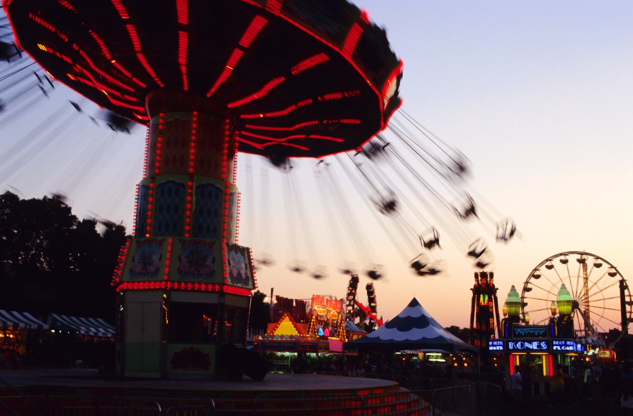 a spinning thrill ride at the Minnesota State Fair is lit up against the colors of the sky at dusk