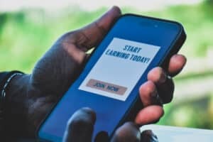 Man decided to join a mobile application to make money online. Digital display on smartphone, side hustle concept.